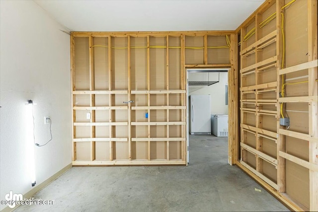 below grade area featuring freestanding refrigerator and baseboards