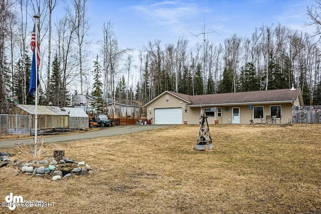 view of front of property featuring aphalt driveway, fence, a front yard, and a garage