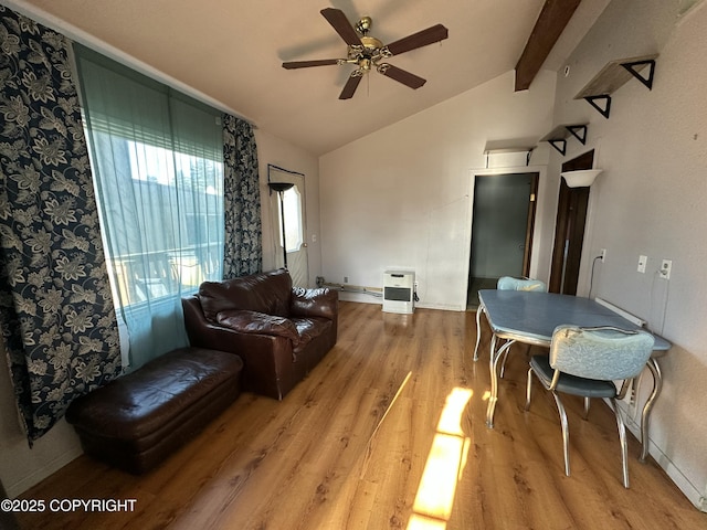 living area with light wood finished floors, heating unit, vaulted ceiling with beams, and ceiling fan