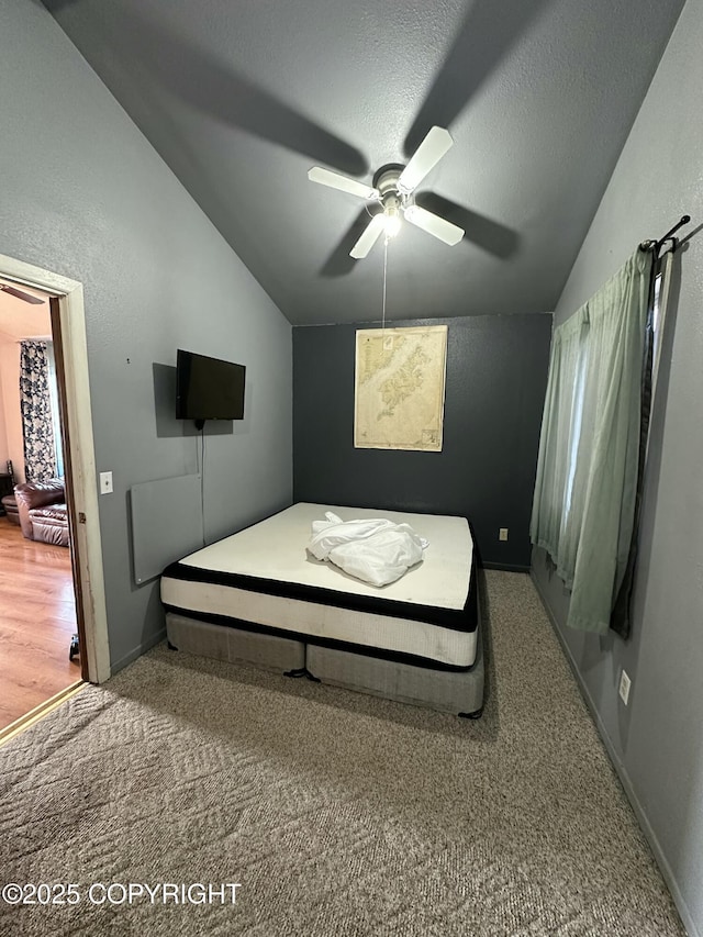 bedroom featuring a ceiling fan, baseboards, lofted ceiling, a textured ceiling, and carpet flooring