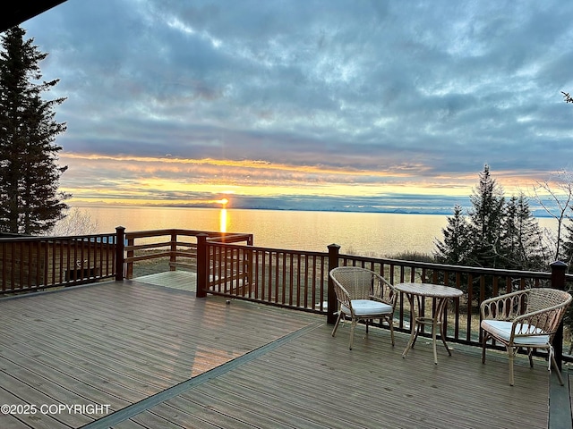 deck at dusk featuring a water view