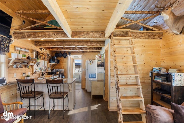 kitchen featuring beam ceiling, wood walls, white fridge with ice dispenser, and dark wood-type flooring