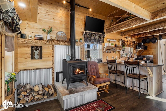 sitting room with wood ceiling, beam ceiling, wood finished floors, wood walls, and a wood stove