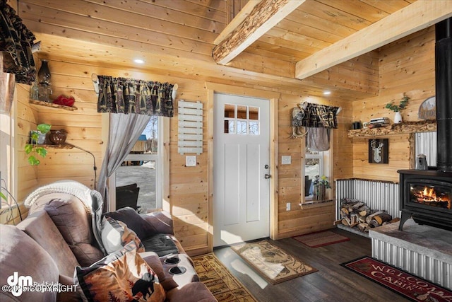 living room with wood walls, wood finished floors, beam ceiling, a wood stove, and wooden ceiling