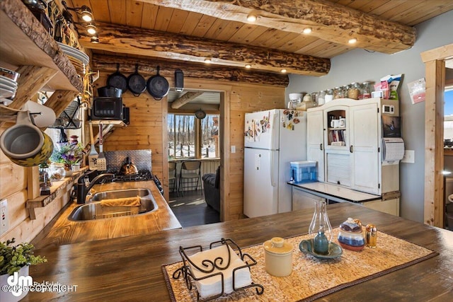 kitchen featuring white appliances, wooden walls, wood ceiling, and a sink