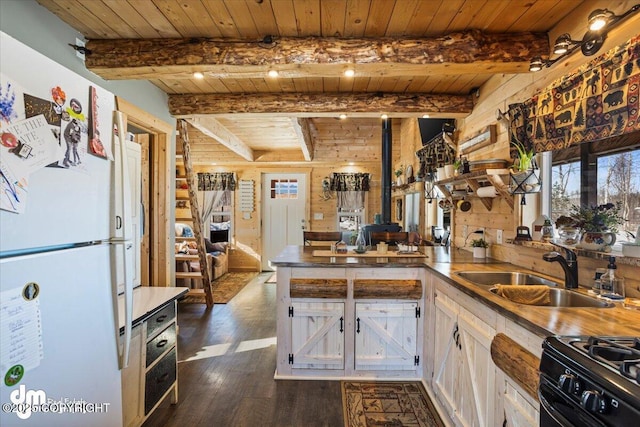 kitchen with a sink, wood ceiling, black gas range oven, freestanding refrigerator, and a peninsula