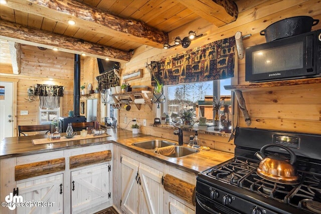 kitchen with wood walls, beamed ceiling, a sink, black appliances, and wooden ceiling