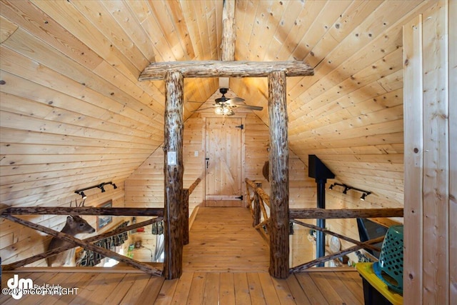 interior space featuring an upstairs landing, wooden walls, vaulted ceiling with beams, wooden ceiling, and wood-type flooring