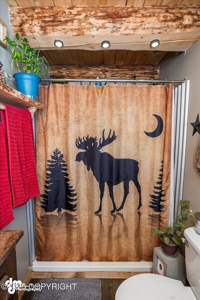 bathroom with toilet, wood ceiling, and curtained shower
