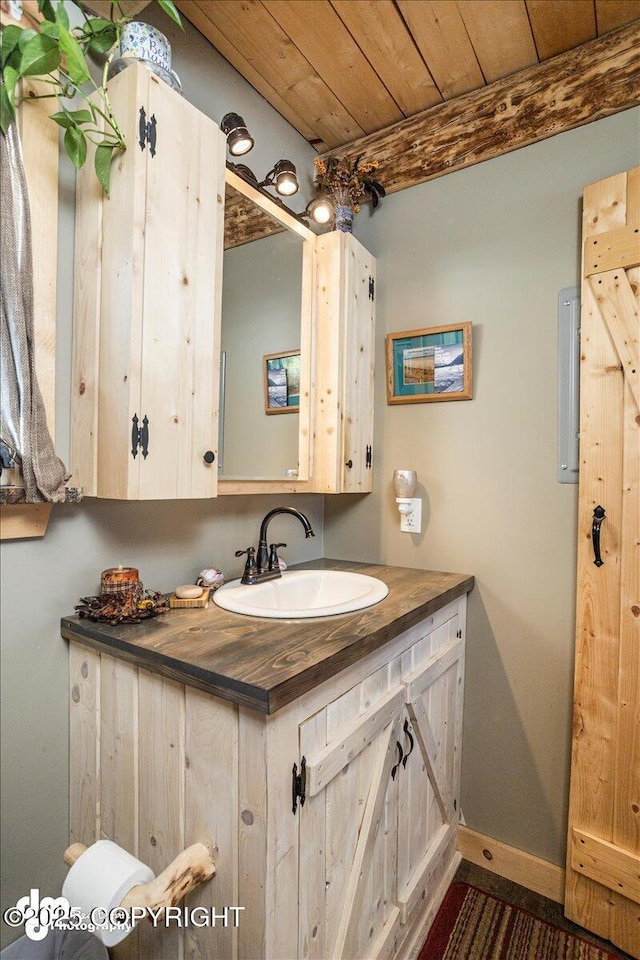 bathroom with baseboards, wooden ceiling, and vanity