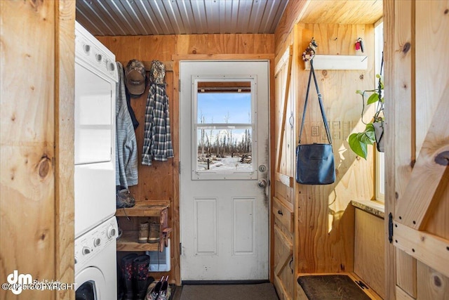 entryway with wood ceiling, stacked washer and clothes dryer, and wood walls