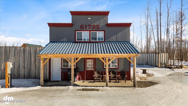 view of front facade with a porch, fence, and metal roof