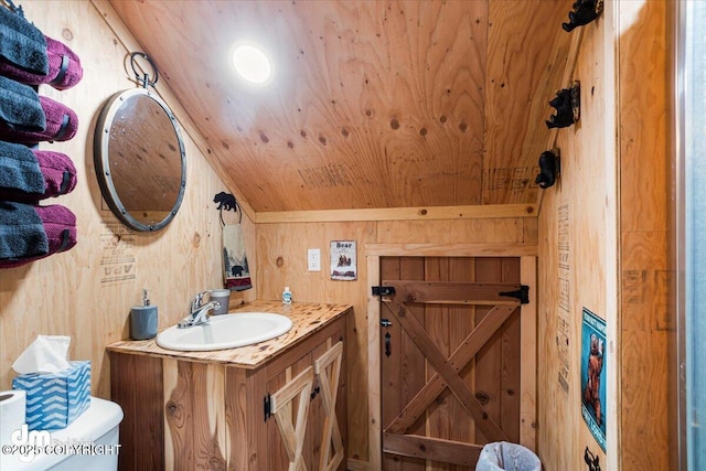 bathroom with vanity, wood walls, lofted ceiling, toilet, and wooden ceiling
