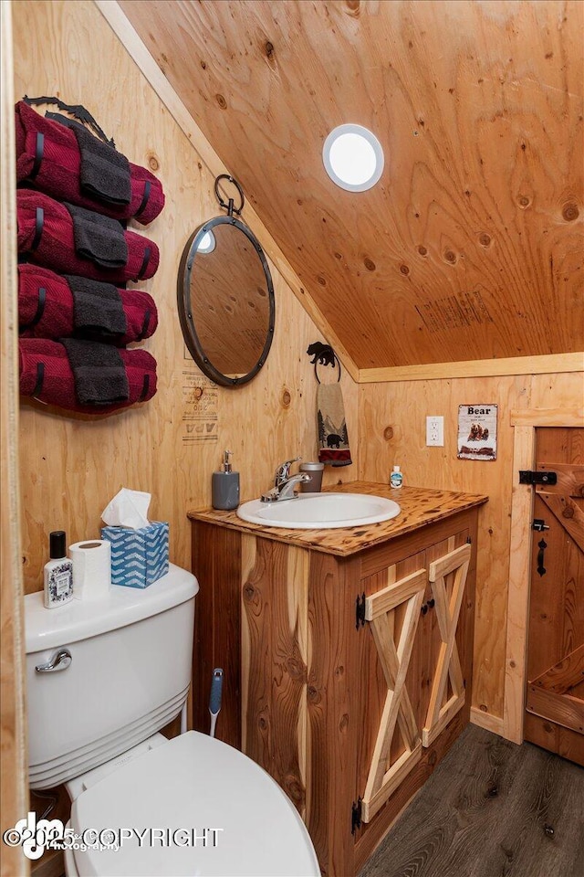 bathroom with vaulted ceiling, toilet, wood ceiling, vanity, and wooden walls