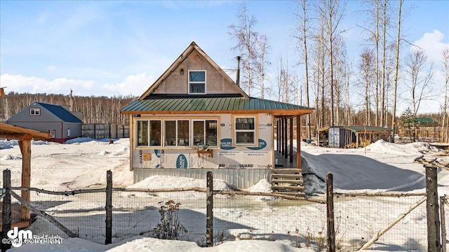 chalet / cabin with covered porch, a fenced front yard, a standing seam roof, and metal roof