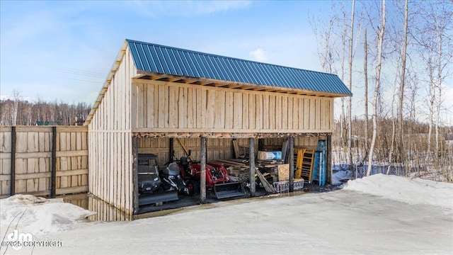 snow covered structure featuring an outbuilding