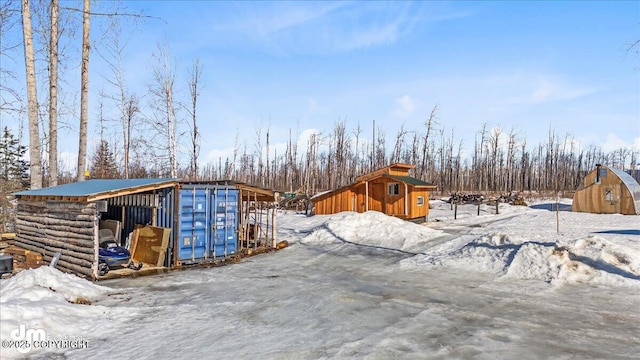 snow covered structure featuring an outbuilding