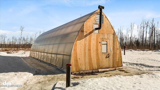 snow covered structure featuring an exterior structure and an outdoor structure