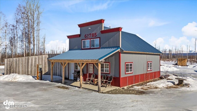 view of front of home with metal roof and fence