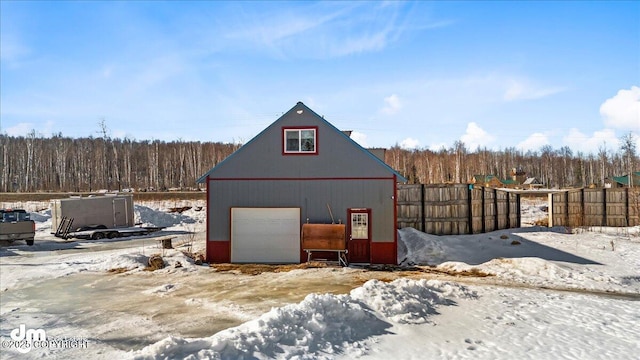 snow covered garage with a garage and fence