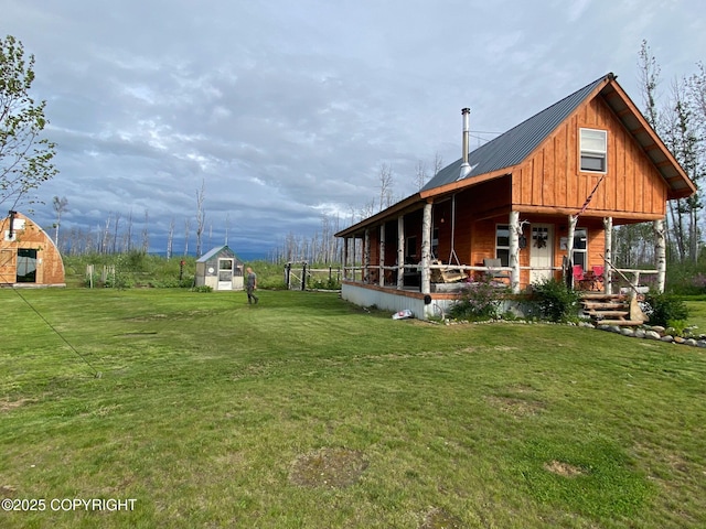 rear view of house with an outdoor structure, a storage shed, metal roof, a porch, and a yard
