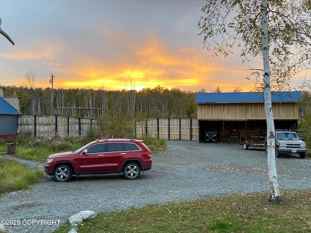 parking at dusk featuring driveway and fence