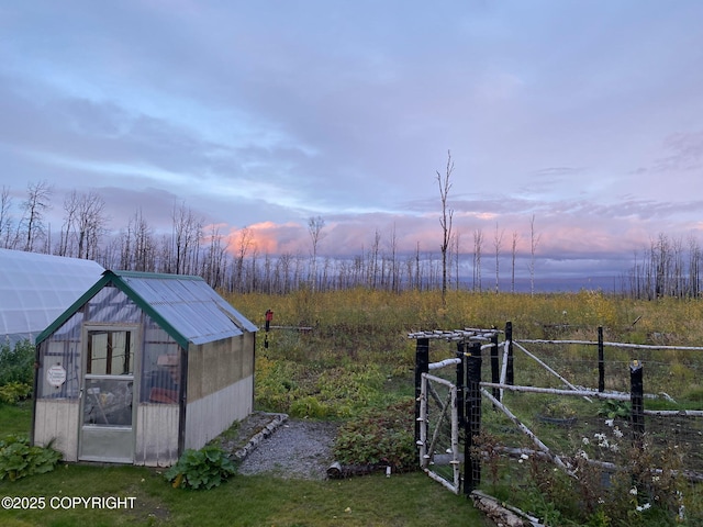 yard at dusk featuring an outbuilding and a greenhouse