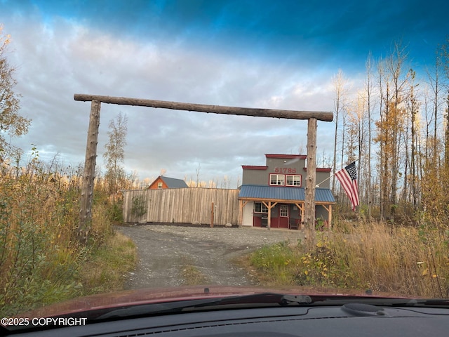 exterior space featuring fence, metal roof, and dirt driveway