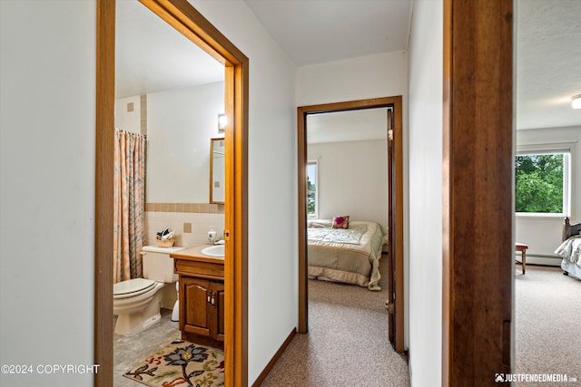 ensuite bathroom with vanity, toilet, ensuite bath, and a baseboard heating unit
