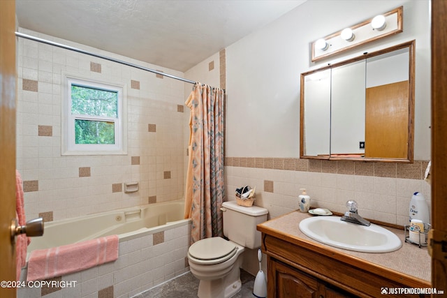 bathroom with vanity, tiled shower / bath, toilet, and tile walls