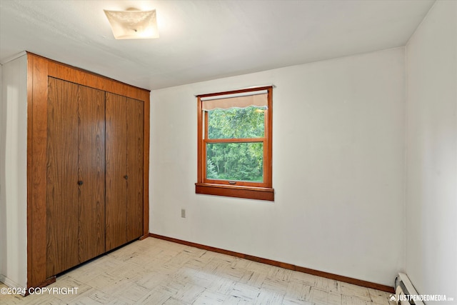 unfurnished bedroom with baseboards, light floors, a baseboard heating unit, and a closet