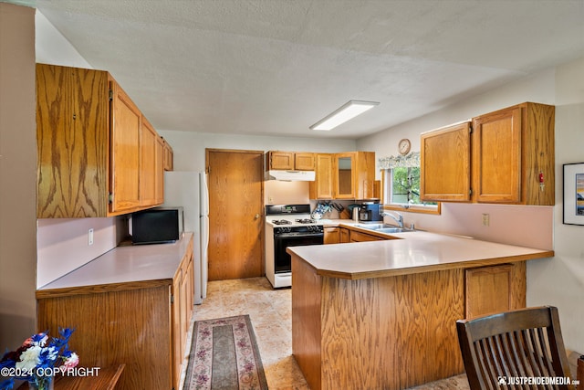 kitchen with a sink, light countertops, brown cabinetry, a peninsula, and gas range