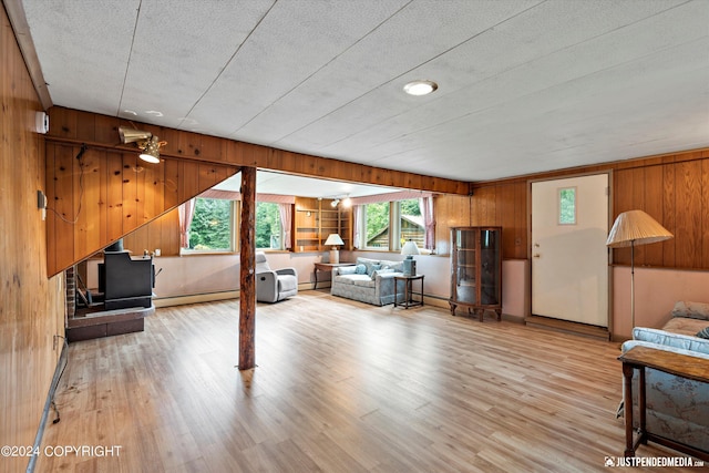 living area featuring wooden walls, baseboard heating, and wood finished floors