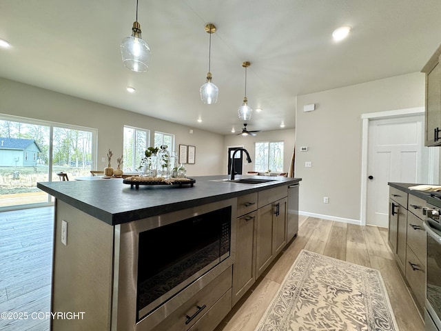 698 Wortham Ave, Kenai, AK 99611 - kitchen with dark countertops, built in microwave, light wood finished floors, an island with sink, and dishwasher