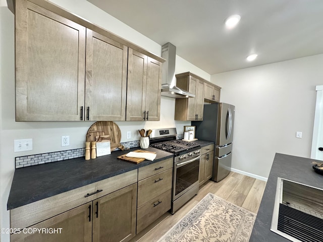698 Wortham Ave, Kenai, AK 99611 - kitchen featuring appliances with stainless steel finishes, wall chimney range hood, dark countertops, light wood finished floors, and recessed lighting