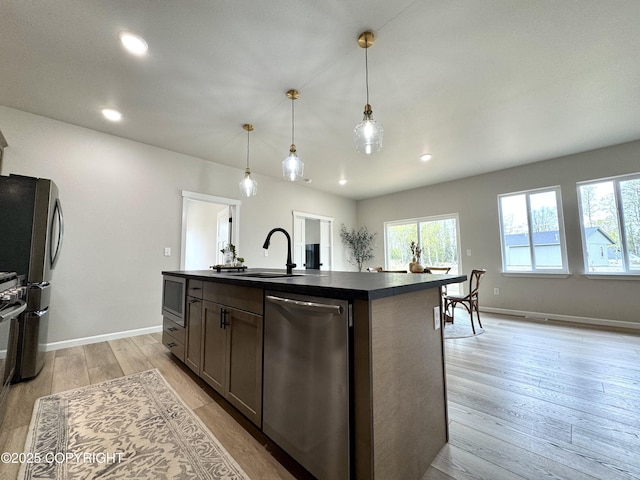 698 Wortham Ave, Kenai, AK 99611 - kitchen featuring stainless steel appliances, dark countertops, light wood-type flooring, recessed lighting, and a center island with sink