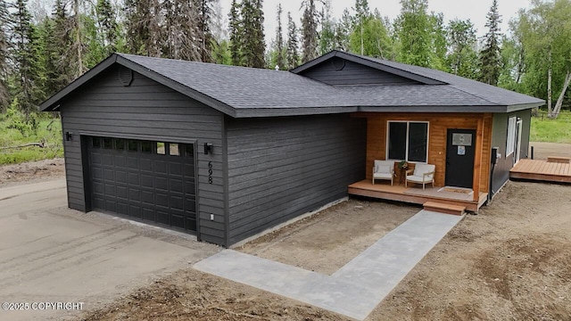698 Wortham Ave, Kenai, AK 99611 - view of front of property featuring a shingled roof, a wooden deck, a garage, and view of scattered trees