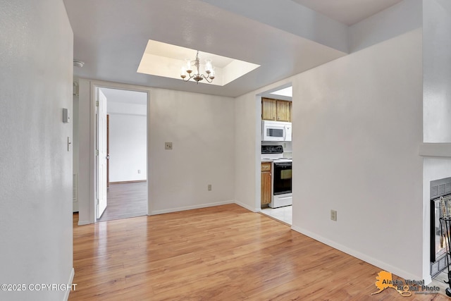 unfurnished dining area featuring a chandelier, light wood-style flooring, and baseboards