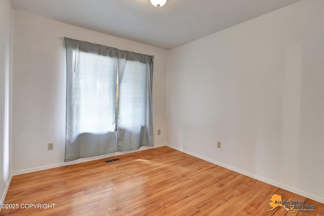 empty room featuring light wood-type flooring and baseboards