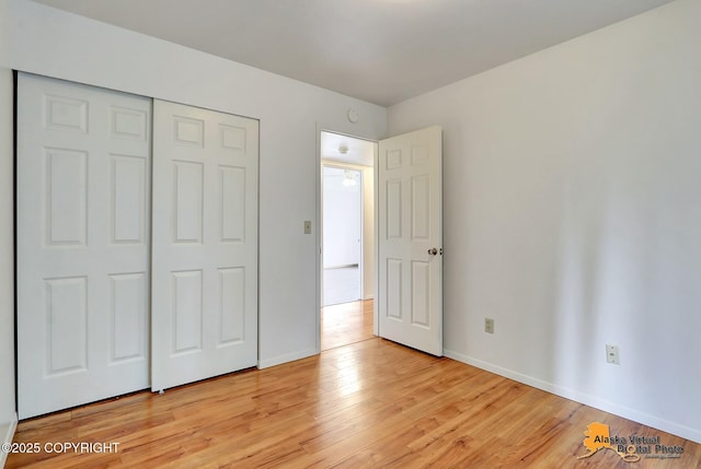unfurnished bedroom with light wood-style flooring, baseboards, and a closet