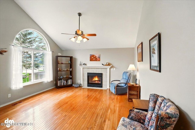 19016 Mountain Point Cir, Eagle River, AK 99577 - living area featuring hardwood / wood-style flooring, a tile fireplace, ceiling fan, baseboards, and high vaulted ceiling