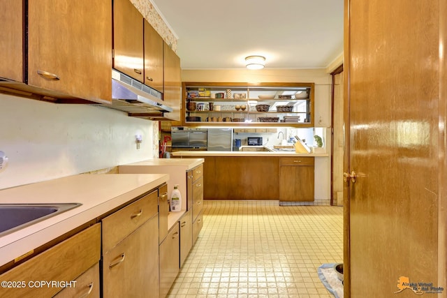 204 E 15th Ave, Anchorage, AK 99501 - kitchen with freestanding refrigerator, brown cabinets, under cabinet range hood, light countertops, and oven
