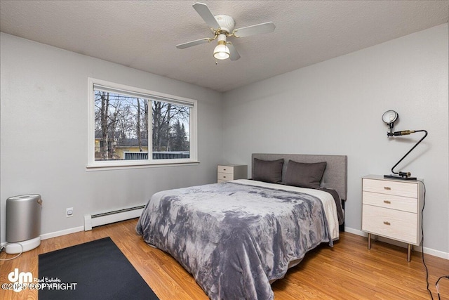 4801 Carousel Cir, Anchorage, AK 99502 - bedroom with baseboards, ceiling fan, a textured ceiling, light wood-style flooring, and a baseboard heating unit