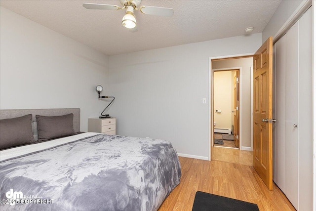 4801 Carousel Cir, Anchorage, AK 99502 - bedroom featuring baseboards, light wood-style floors, a baseboard heating unit, and a textured ceiling