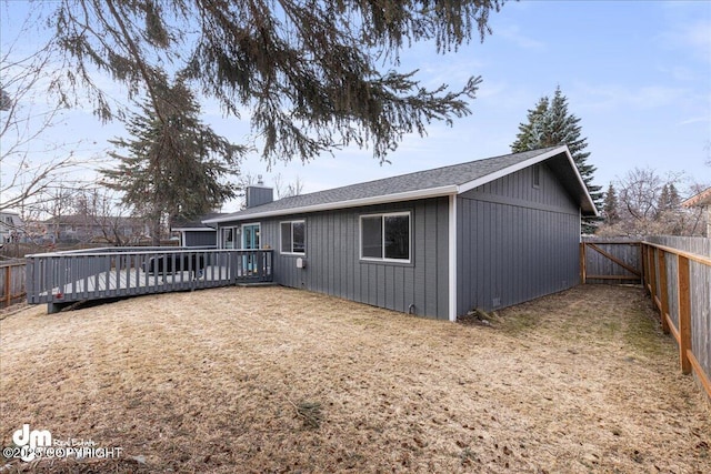 4801 Carousel Cir, Anchorage, AK 99502 - back of property with a chimney, a fenced backyard, a wooden deck, and a lawn