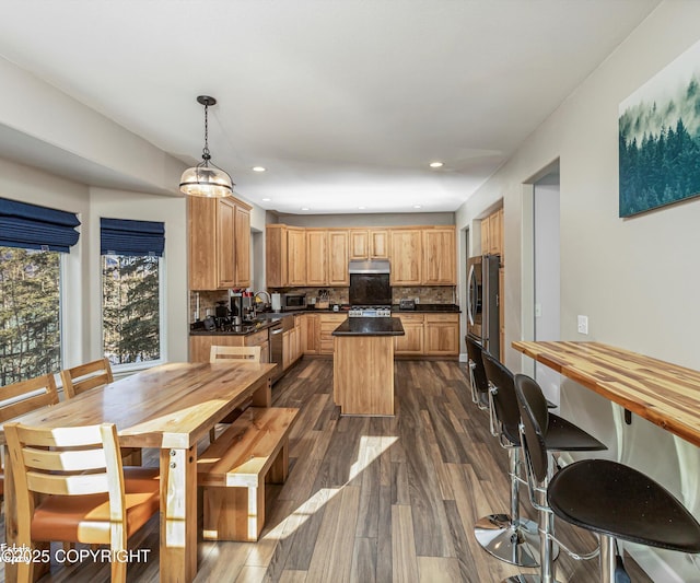 25656 Bendilent Cir, Eagle River, AK 99577 - kitchen with a center island, dark wood-style floors, under cabinet range hood, recessed lighting, and backsplash