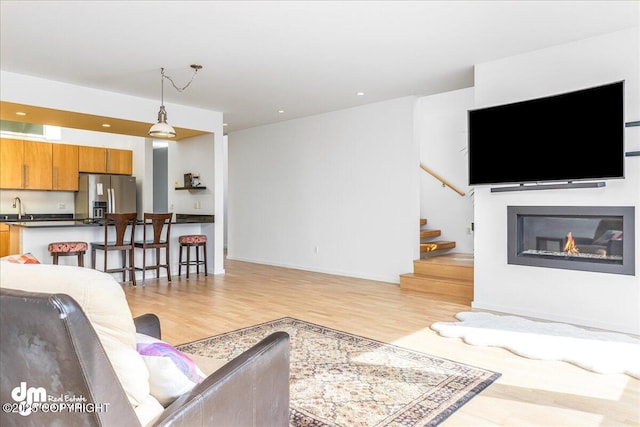 1382 Northbluff Dr # 4B, Anchorage, AK 99501 - living room with light wood-style floors, baseboards, a glass covered fireplace, and stairs