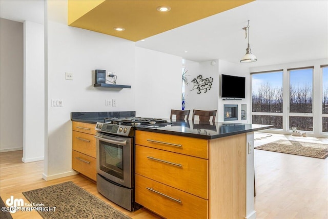 1382 Northbluff Dr # 4B, Anchorage, AK 99501 - kitchen with stainless steel gas range oven, dark countertops, light wood-style floors, a glass covered fireplace, and open floor plan