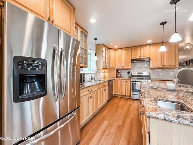 6934 Inlet Vista Dr, Wasilla, AK 99623 - kitchen featuring stainless steel appliances, under cabinet range hood, light wood-style floors, glass insert cabinets, and decorative backsplash