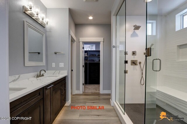 16074 Mountain Air Dr, Anchorage, AK 99516 - bathroom featuring double vanity, a stall shower, a walk in closet, wood finished floors, and baseboards